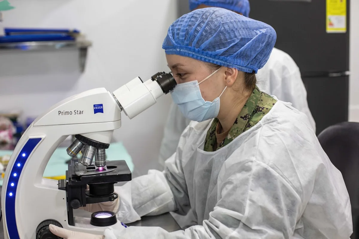 A laboratory professional works at a microscope